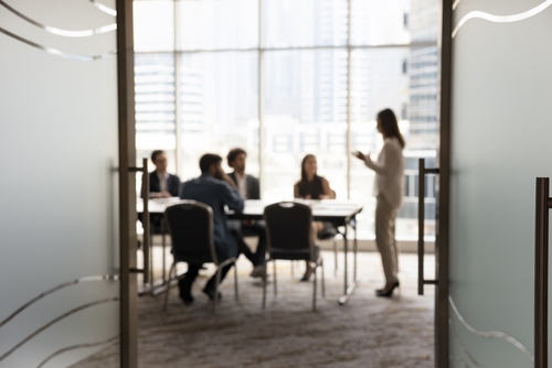 Photograph of people standing and sitting around a Board room table and chairs