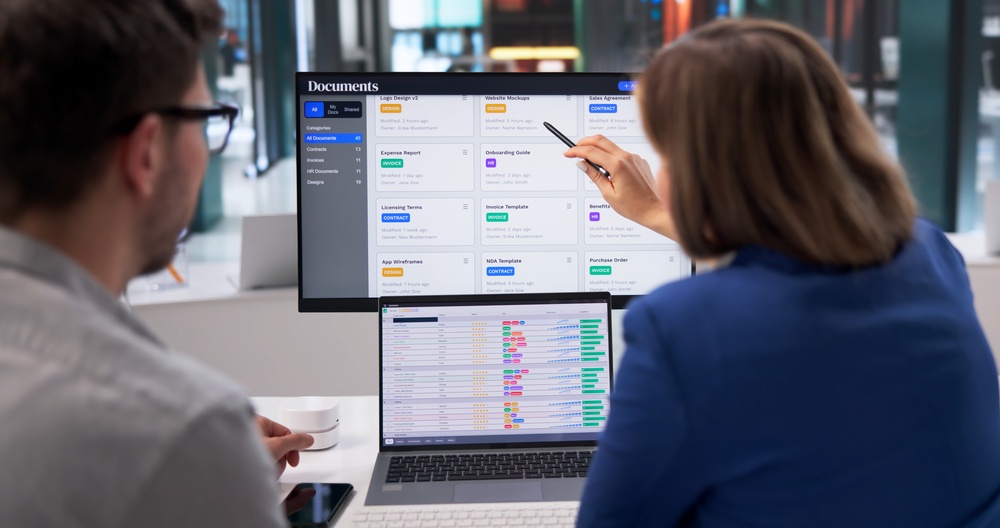Two professional people looking at some information on a computer monitor