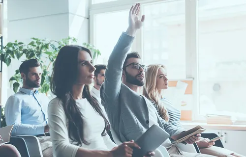 photo of a man raising his hand to ask a question