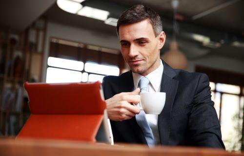 A businessman with a cup in his hand and looking at iPad